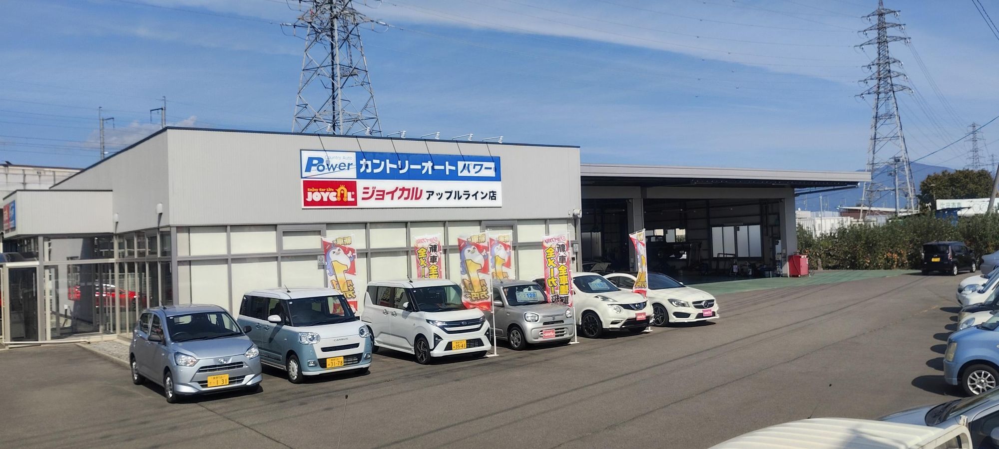 カントリーオートパワー ジョイカル アップルライン店の看板と店舗、右奥の整備工場